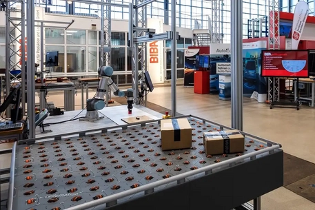 Cellumation-Fördersystem mit multidirektionalen Rollen und Roboterarm in der BIBA-Forschungshalle für intelligente Logistiklösungen und Automatisierung.